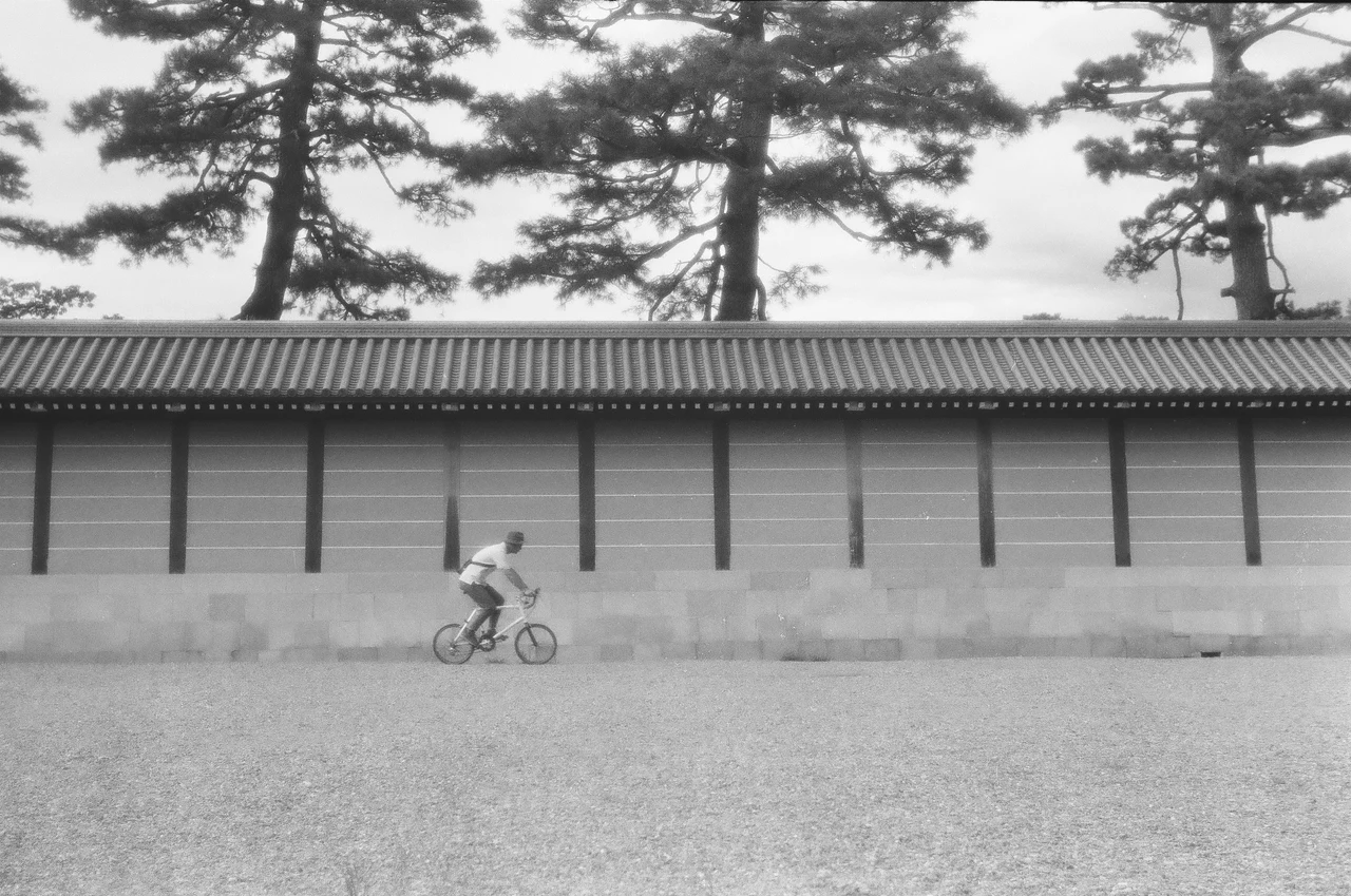 塀沿いを自転車で走る人